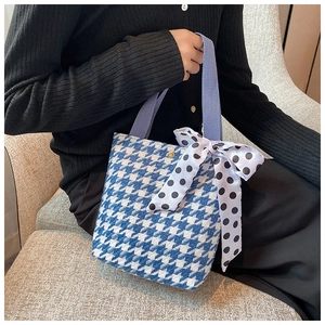 Detail of blue houndstooth woven handbag featuring a large polka dot bow accessory