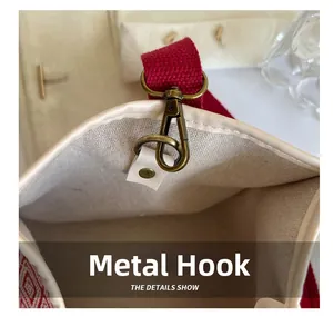 Close-up of vintage bronze metal hook on off-white canvas and red woven strap