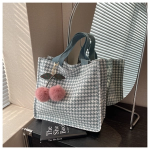 Detail of blue and white houndstooth tote bag with cute pink cherry plush pendant charm