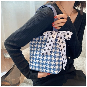 Close-up of houndstooth canvas handbag with a black and white polka dot silk bow detail