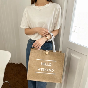 Macro view of jute tote bag with HELLO WEEKEND print, woven handles and wood buckle