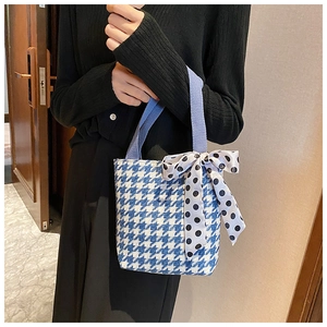 Detail of blue houndstooth tote bag with a polka dot bow and purple handles