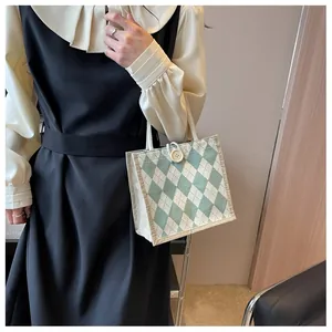 Detail of green argyle canvas tote bag with woven texture and button closure