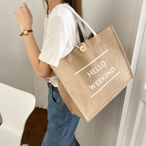 Detailed view of large jute tote bag with 'HELLO WEEKEND' print and wooden button