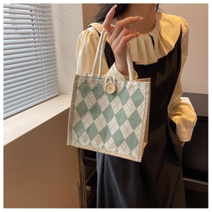 Detail view of canvas tote bag with green argyle pattern and vintage large button