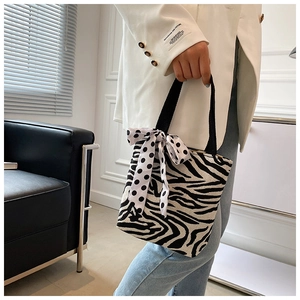 Close-up of zebra pattern knitted handbag with a polka dot ribbon on the handle