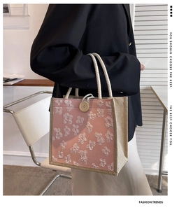 Détail latéral du sac cabas en lin avec broderie florale rose et poignée en corde blanche
