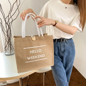 Detail of jute tote bag with HELLO WEEKEND print, white rope handle and wooden button