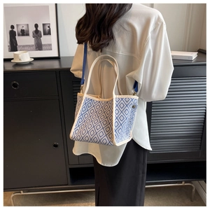 Blue and white geometric canvas bucket bag with adjustable straps in a modern lifestyle setting
