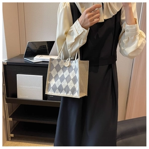 Detail view of woven grey argyle canvas tote bag with button closure and braided handles