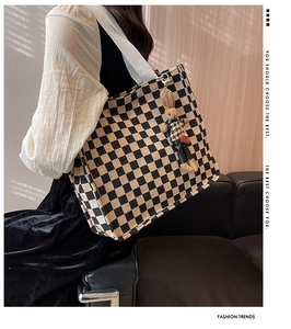 Detail of checkered canvas tote bag with a cute rabbit plush charm and wide strap