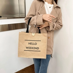 Linen tote bag with black Hello Weekend print and round buckle detail in a casual setting