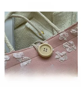 Détail du sac à main rose en tissu avec jacquard floral 3D et bouton en bois