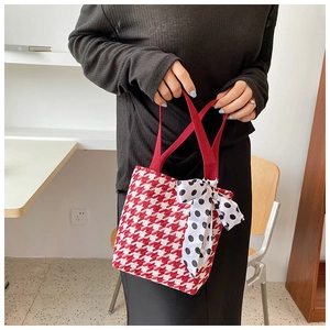 Close-up of red houndstooth tote bag with a black and white polka dot ribbon bow