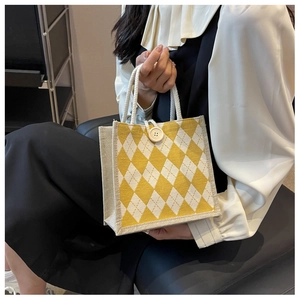 Detail of yellow argyle canvas tote bag with white rope handles and decorative button closure