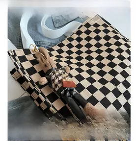 Close-up of a cute knitted rabbit charm with houndstooth coat on a checkerboard canvas bag