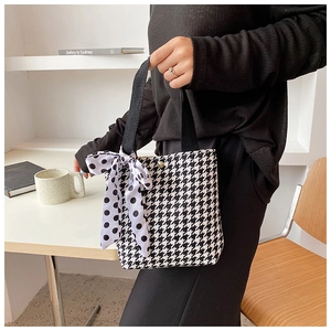 Detail of black and white houndstooth handbag with a polka dot silk scarf handle decor