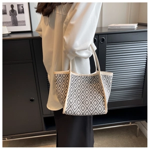 Detail of geometric monochrome tote bag with cream leather handles and woven pattern
