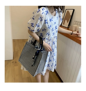 Detail of houndstooth canvas tote bag with silk scarf on handle held by model