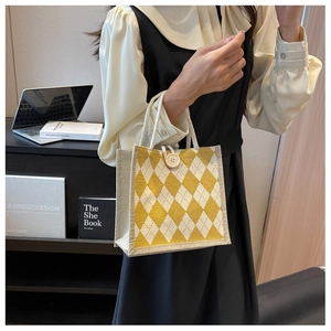 Detail of canvas tote bag showing yellow argyle pattern and rope handle in a desk setting