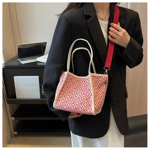Detail of red jacquard tote bag with woven texture and adjustable shoulder strap