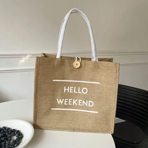 Jute tote bag featuring white Hello Weekend print and woven rope handles on a white table