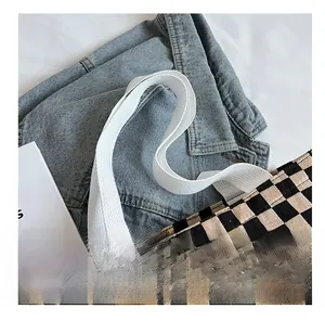 Detail of checkerboard canvas tote bag featuring wide woven handles and metal ring