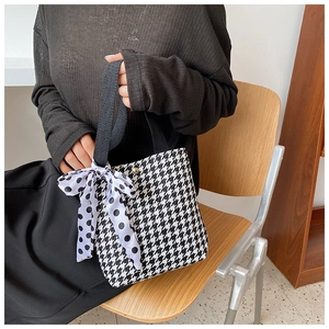 Detail of houndstooth tote bag with polka dot ribbon handle and golden clasp