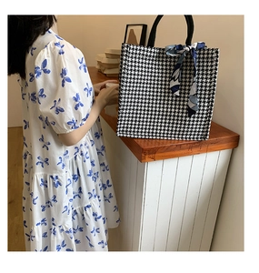 Detail of houndstooth canvas tote bag with a decorative blue patterned silk scarf