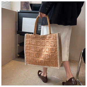 Détail du sac cabas en toile montrant la texture frangée et les poignées tissées