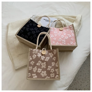 Détail de sacs en toile à fleurs gaufrées avec poignées en corde et bouton en bois