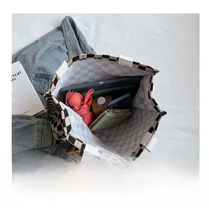 Detail showing the large capacity and checkered canvas interior with everyday essentials