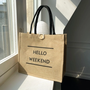 Detail of jute tote bag with Hello Weekend print, round handles and wooden button closure