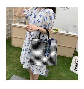 Detail of houndstooth canvas tote bag with decorative silk scarf and black handle