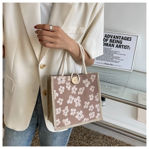 Detail of small woven tote bag with daisy pattern and rope handle shown with an outfit