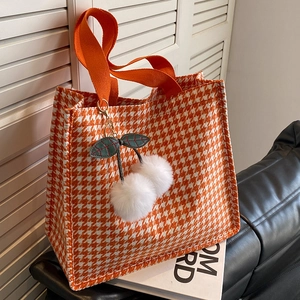 Orange houndstooth knit tote bag with plush cherry charm on a clean background