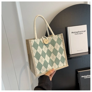 Detail of green argyle canvas tote bag with rope handle and wooden button closure