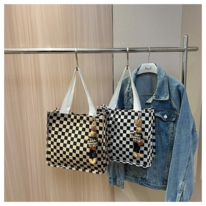 Close-up of checkerboard canvas tote bags with cute bunny pendants and woven handles