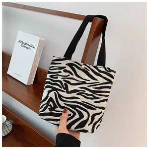 Detail of zebra pattern canvas handbag with black fabric handle and gold metal buckle