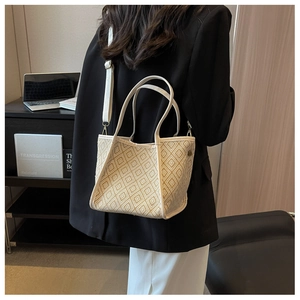 Detail of a beige geometric woven tote bag with white leather trim and shoulder strap