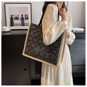 Détail d'un grand sac fourre-tout en toile texturée tweed porté à l'épaule par un modèle