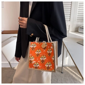 Detail of cartoon tiger print on orange linen tote bag with woven cotton rope handle