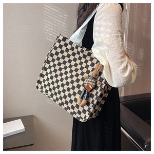 Detail of checkered canvas tote bag with a cute plush bunny pendant on the shoulder strap