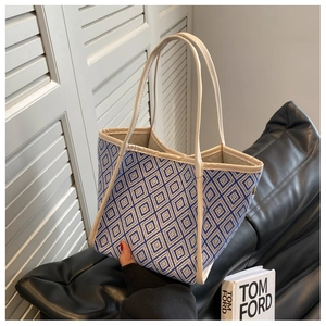 Detail of blue and white geometric diamond pattern tote bag with cream leather handles