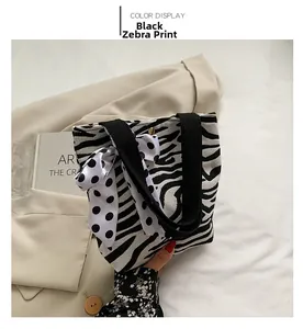 Close-up of zebra pattern canvas tote with polka dot scarf and gold metal buckle