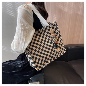 Detail of checkered canvas tote bag featuring a cute rabbit charm and woven shoulder straps