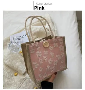 Vue détaillée du sac en jute rose avec motifs floraux et fermeture par bouton en bois