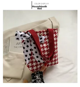 Detail of red houndstooth canvas handbag with polka dot ribbon bow and fabric handle