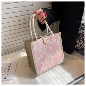 Detail of pink woven tote bag with 3D floral appliques and braided rope handle
