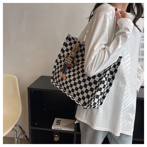 Detail view of checkerboard canvas tote bag with cute rabbit pendant and sturdy shoulder strap